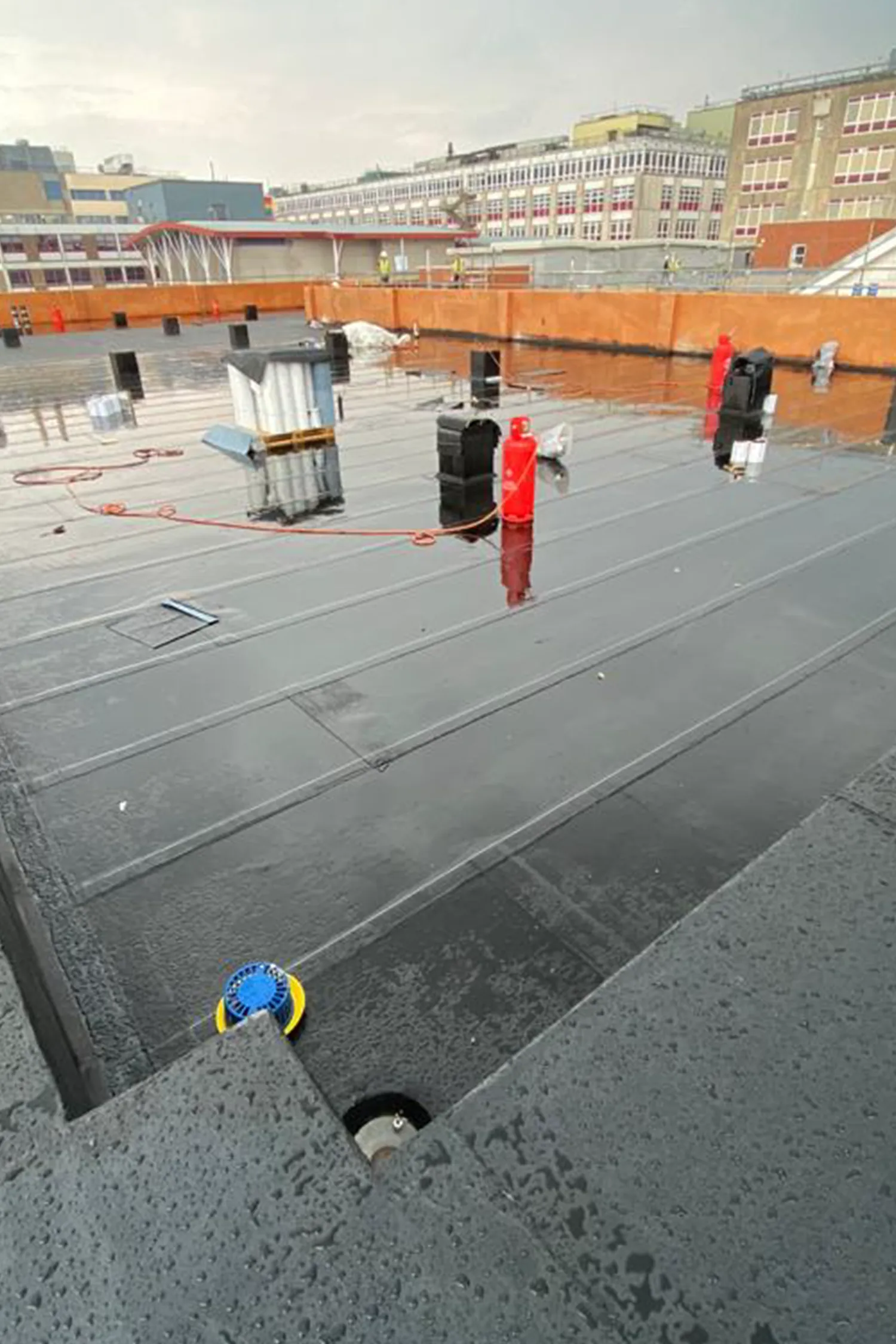 Rooftop construction site with safety equipment and building infrastructure visible